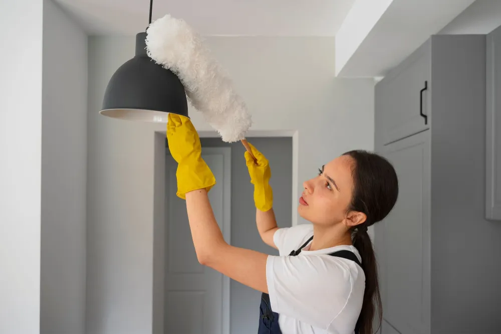 Huishoudhulp maakt een lamp schoon en helpt bij het dagelijkse huishouden.